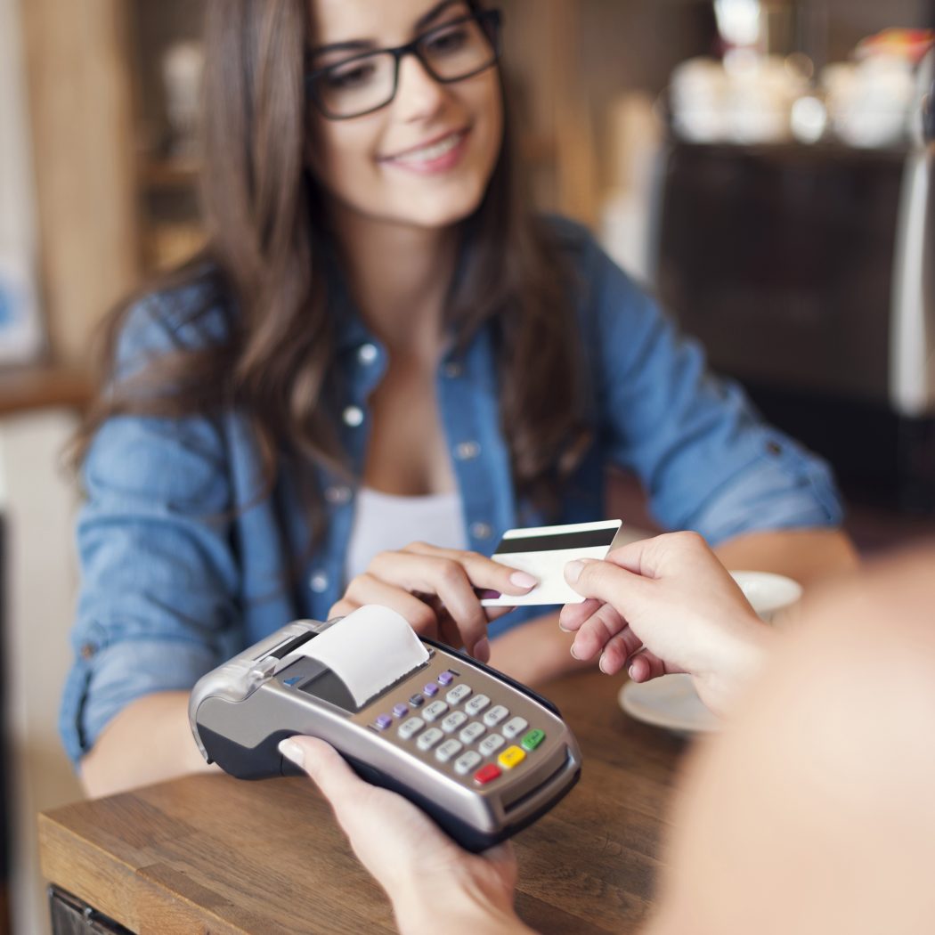 Smiling woman paying for coffee by credit card